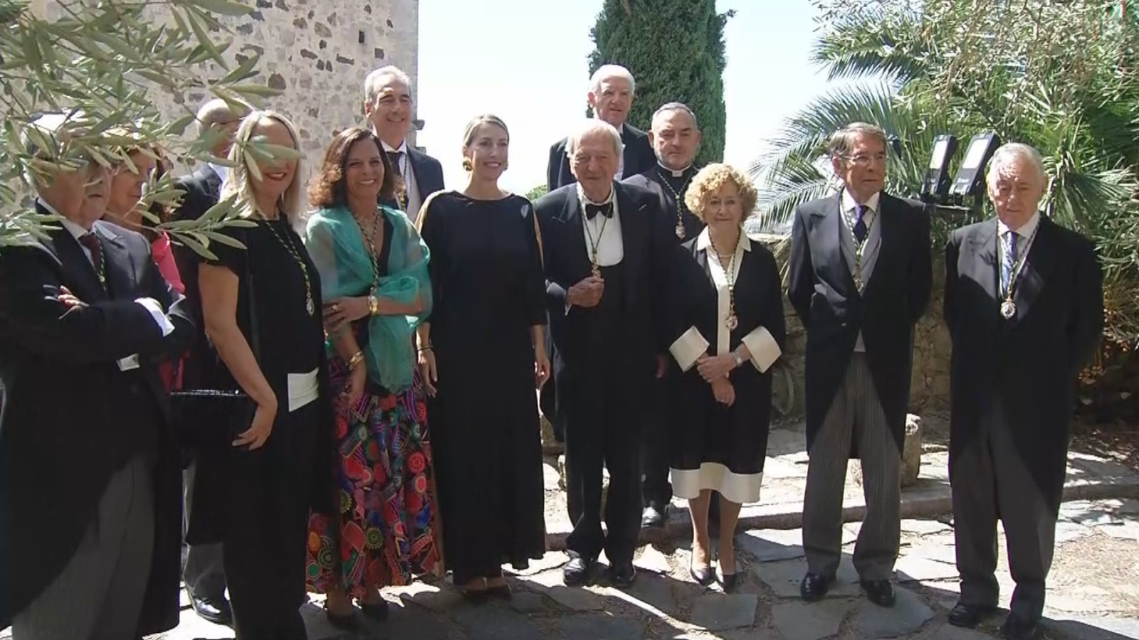 Rafael Moneo, arquitecto español, posa con un grupo de doce personas en un evento formal al aire libre. Viste chaqué y una medalla dorada, rodeado de hombres y mujeres con vestimenta elegante.