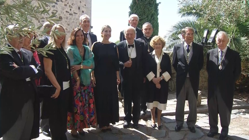 Rafael Moneo, arquitecto español, posa con un grupo de doce personas en un evento formal al aire libre. Viste chaqué y una medalla dorada, rodeado de hombres y mujeres con vestimenta elegante.