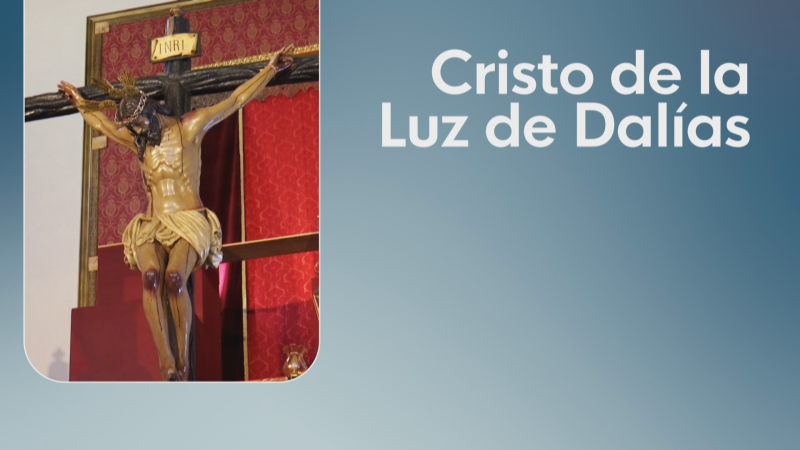 Escultura de Cristo crucificado con inscripción "INRI" y el texto "Cristo de la Luz de Dalías" sobre fondo azul.