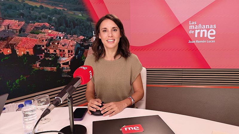 Irene Montero sonríe a la cámara en un estudio de radio, con un micrófono rojo 'rne' y un portátil frente a ella. El fondo muestra un paisaje y el logo de 'Las mañanas de rne'.