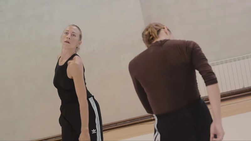 Dos bailarinas con ropa deportiva Adidas en un espacio interior, una de frente y otra de espaldas, en pose de movimiento.
