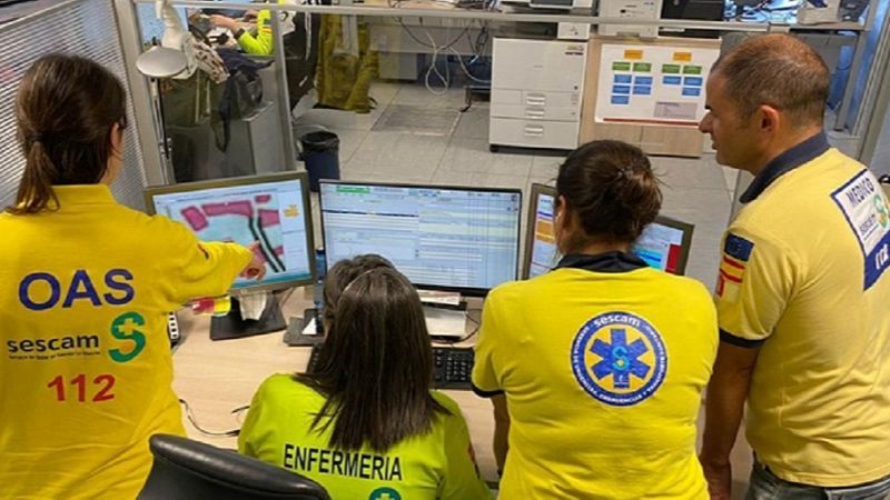 Profesionales del SESCAM, incluyendo médico y enfermería, coordinan emergencias frente a pantallas con mapas y datos. Se aprecian logos del 112 y UVI Móvil.