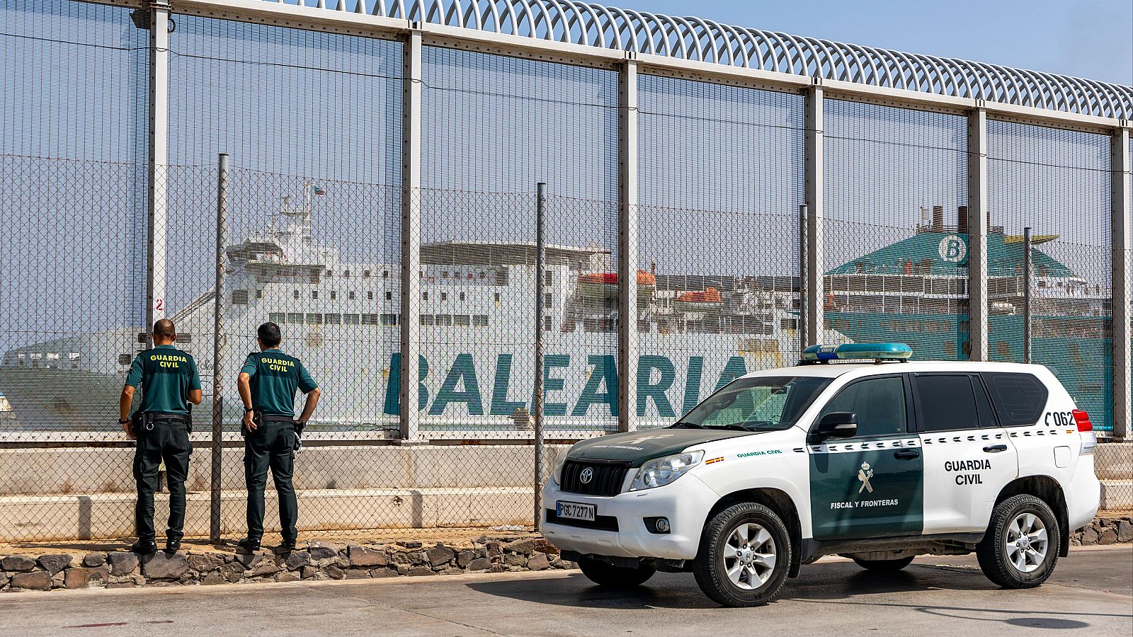Agentes de la Guardia Civil y un vehículo "FISCAL Y FRONTERAS" en el Dique Sur de Melilla, con un ferry de Balearia al fondo.