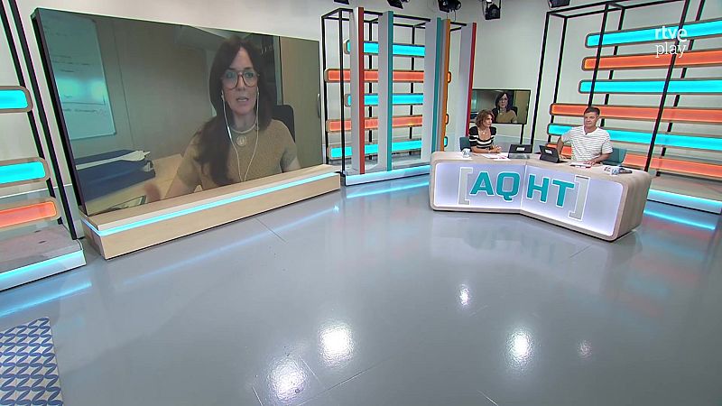 Plató de televisión con presentadores Marta Cillán y Jon Ariztimuño, escritorio "AQHT" y pantalla con participante remota. Fondo con luces azules/celestes y naranjas/rojizas, logo "rtve play".