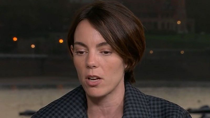 Victoria Luengo, actriz española, en un primer plano con expresión seria. Lleva chaqueta de cuadros y el fondo está desenfocado con luces cálidas.