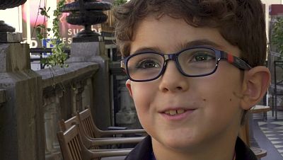 Pablo Conesa, actor espa�ol, sonr�e con gafas azules y un lanyard oscuro. Al fondo, un cartel con "SU" y "FES" indica el Festival de San Sebasti�n.