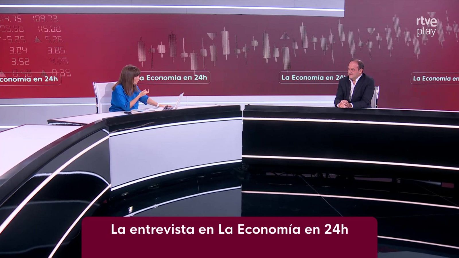 Ana Ibáñez y José Carlos Díez en "La Economía en 24h" de RTVE, con gráficos financieros de fondo.