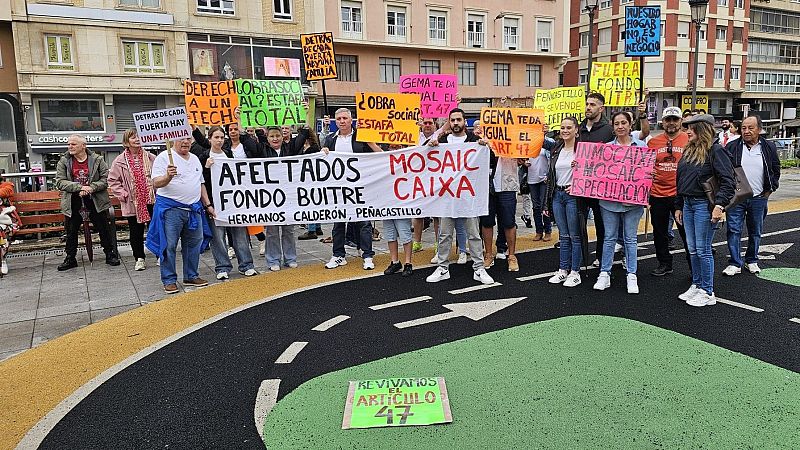 Grupo de manifestantes concentrados frente a un edificio de viviendas en la calle Hermanos Calderón, Cantabria, sosteniendo pancartas con lemas por el derecho a la vivienda y contra los desahucios.