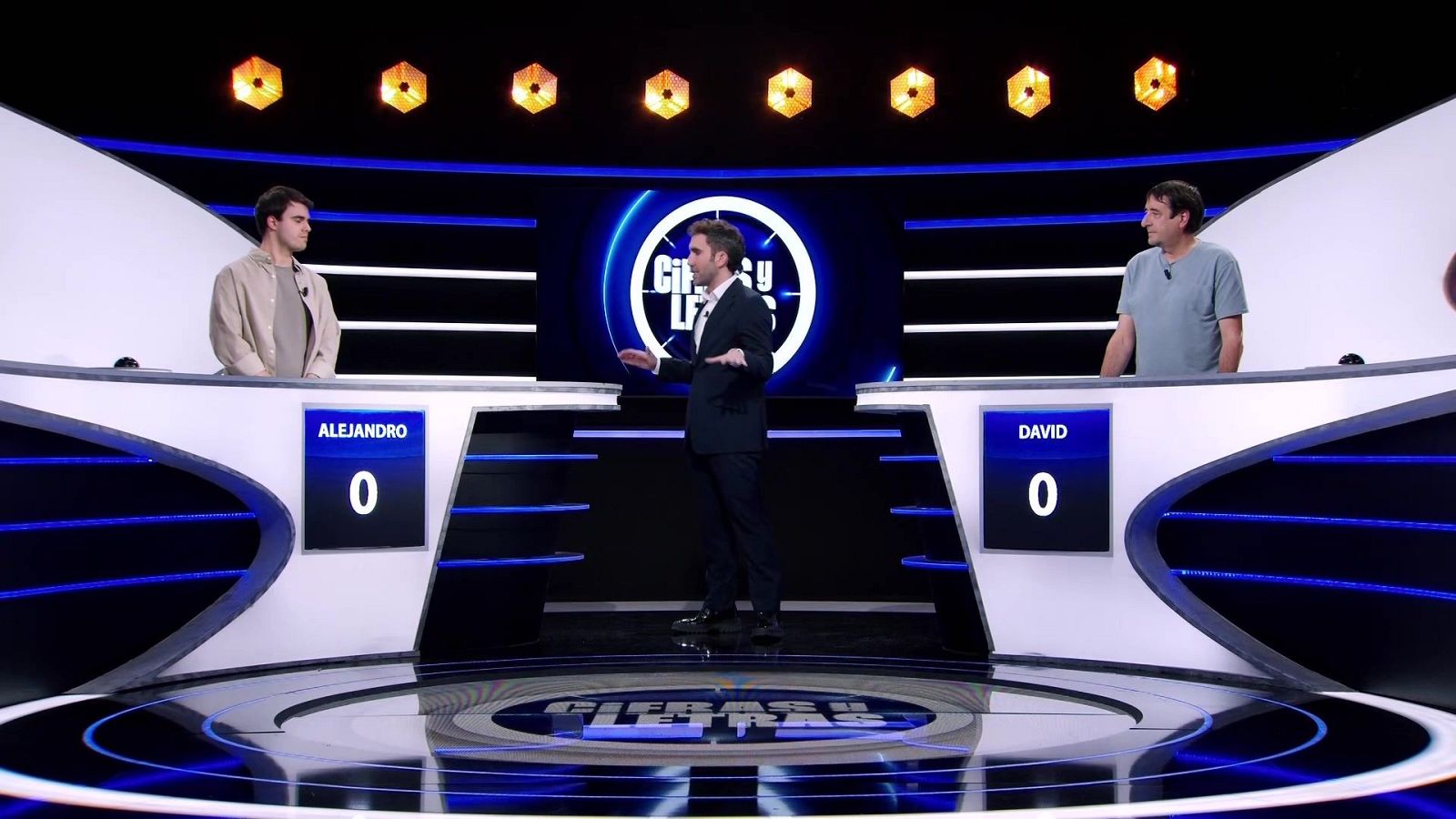 Aitor Albizua presenta "Cifras y letras" a los concursantes Alejandro y David, ambos con puntuación de 0 en sus atriles.