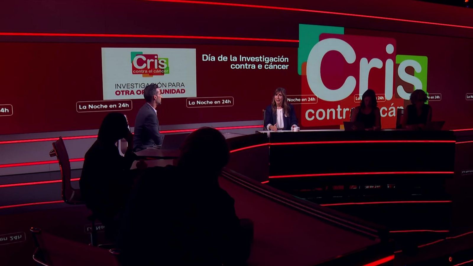 Marta Solano en plató de "La Noche en 24h", con logo "Cris contra el cáncer" y pantalla de fondo.