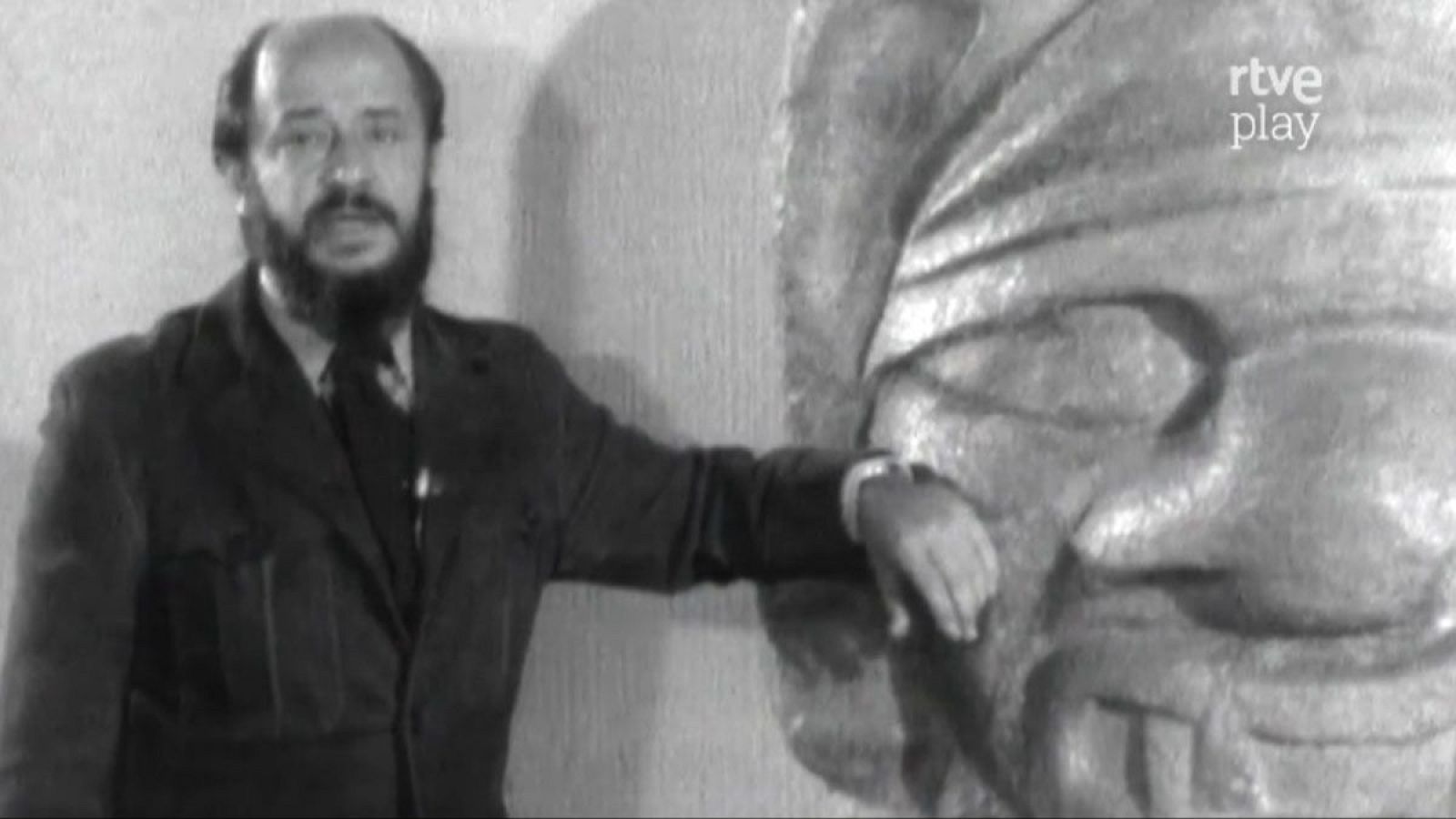 Fernando Jiménez del Oso, con gafas y barba, posa junto a una escultura de rostro pétreo. Logo "rtve play" en la esquina superior derecha.