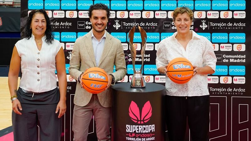 Miriam Gutiérrez, Alejandro Navarro y una mujer posan con balones de baloncesto "Wilson LF Endesa" junto a un trofeo de la "SUPERCOPA -LF endesa- TORREJÓN DE ARDOZ" frente a un fondo corporativo.