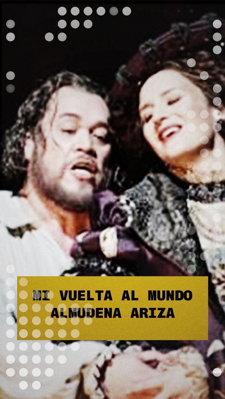 Un hombre canta apasionadamente junto a Almudena Ariza, quien sonríe. El recuadro amarillo en la parte inferior anuncia "MI VUELTA AL MUNDO ALMUDENA ARIZA".