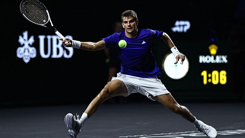 Jugador de tenis en acci�n, golpeando la pelota con raqueta. Logos de UBS, ATP y Rolex visibles en el fondo.