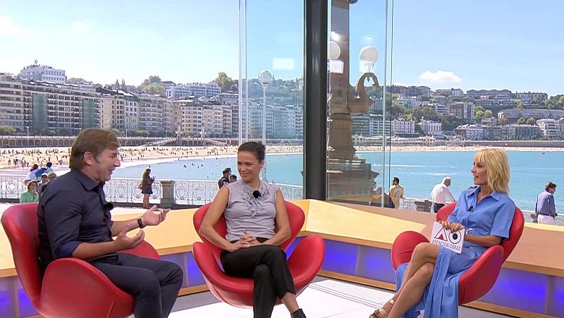 Javier Cámara y Cayetana Guillén Cuervo en "Atención Obras" con vistas a la Bahía de La Concha. Ella sostiene un cartel del programa.