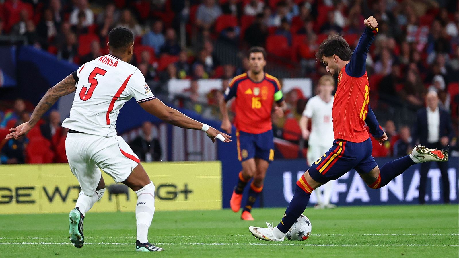 Momento de acción en un partido de la UEFA Nations League: Dani Olmo (España) patea el balón ante la defensa de Ezri Konsa (Inglaterra), con Rodri (España) y público de fondo.