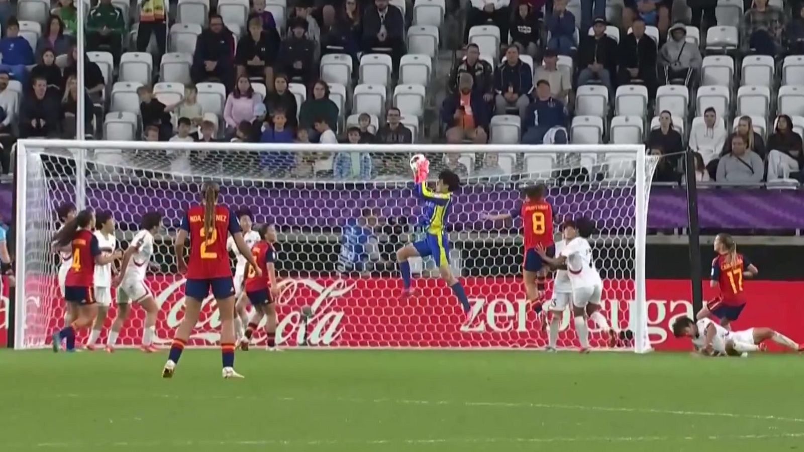 Intensa jugada de fútbol femenino: portera salta, jugadoras se aglomeran. Se ve a la jugadora MÉNDEZ (dorsal 2) y publicidad de Coca-Cola.