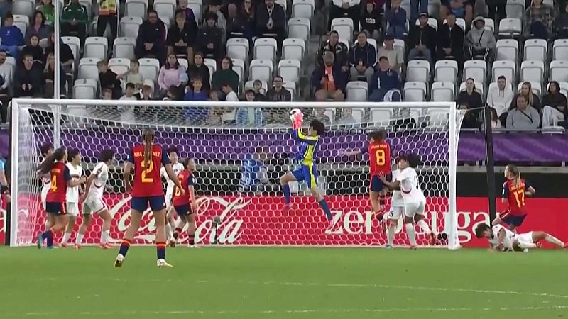Intensa jugada de fútbol femenino: portera salta, jugadoras se aglomeran. Se ve a la jugadora MÉNDEZ (dorsal 2) y publicidad de Coca-Cola.