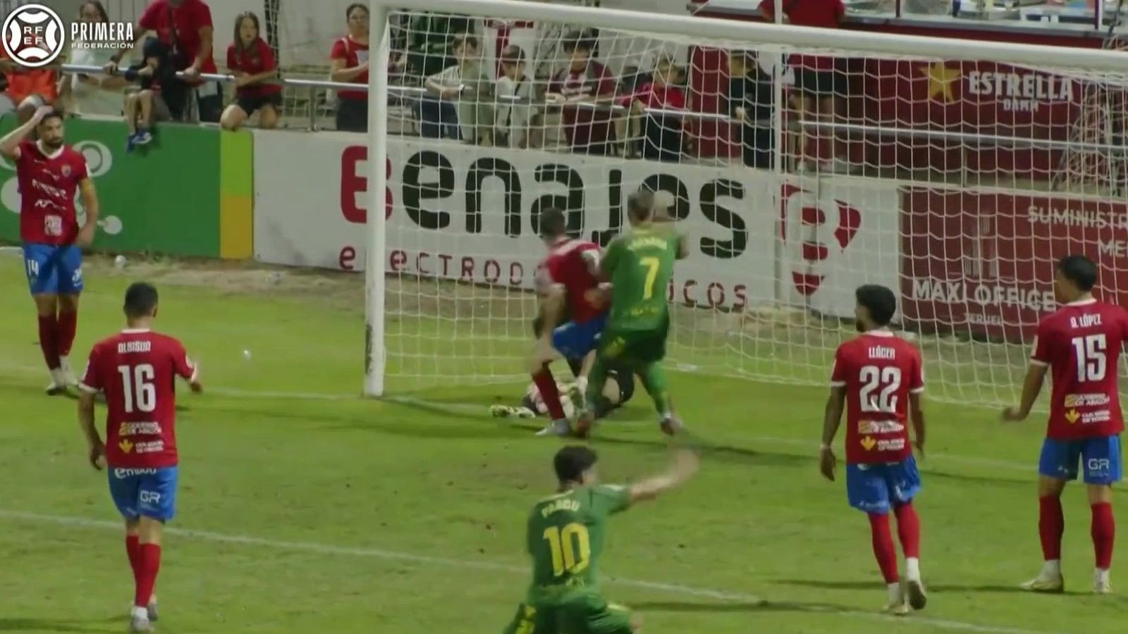 Jugadores de la Primera Federación en acción. "PARDO" (10) del equipo verde reacciona en el césped, mientras jugadores del equipo rojo (incluyendo "ALONSO" 16, "LLACER" 22, "A. LÓPEZ" 15) muestran decepción.