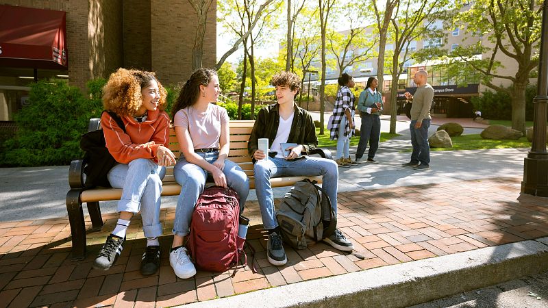 Estudiantes universitarios esperan el autobús en el campus.