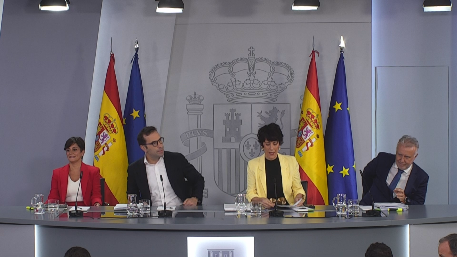 Pilar Alegría, Carlos Cuerpo, Isabel Rodríguez y José Luis Escrivá comparecen en la sala de prensa de la Moncloa ante el escudo de España y banderas oficiales.
