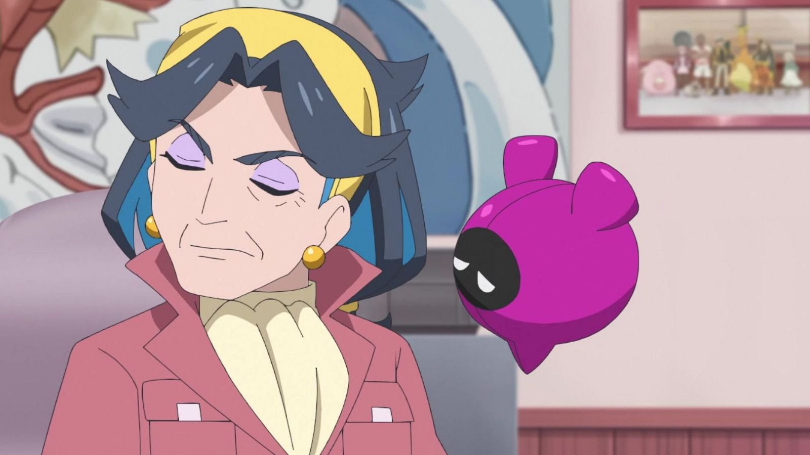 Plano medio de Diana, de Horizontes Pokémon, con expresión serena, bandana amarilla y cabello gris con azul, junto a un dispositivo flotante morado en una habitación rosa.