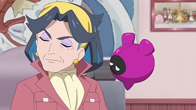 Plano medio de Diana, de Horizontes Pokémon, con expresión serena, bandana amarilla y cabello gris con azul, junto a un dispositivo flotante morado en una habitación rosa.