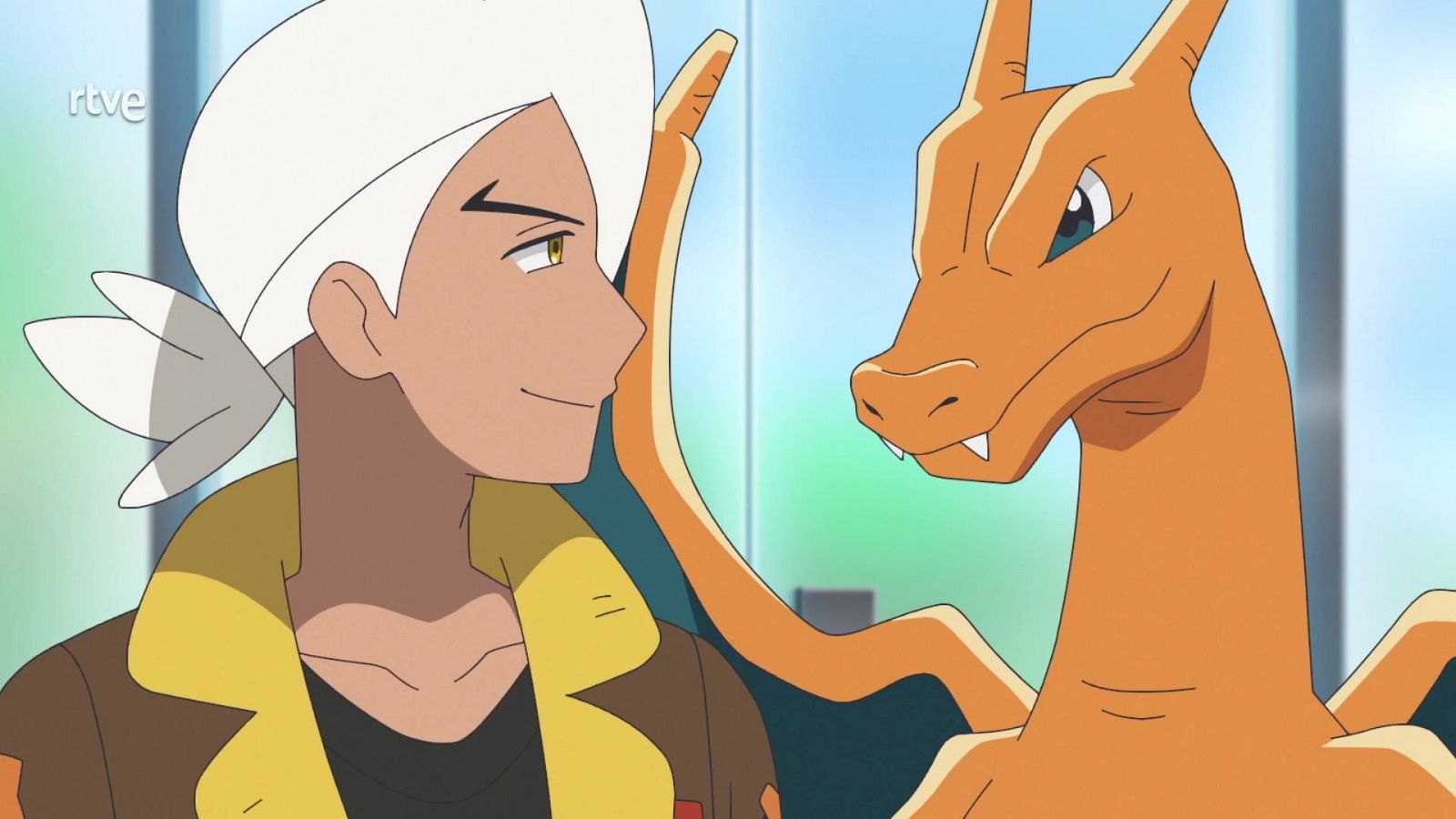 Friede, un joven de cabello blanco, sonríe afectuosamente a su Pokémon Charizard en una escena de Pokémon Horizontes, con el logotipo de rtve en la esquina superior izquierda.