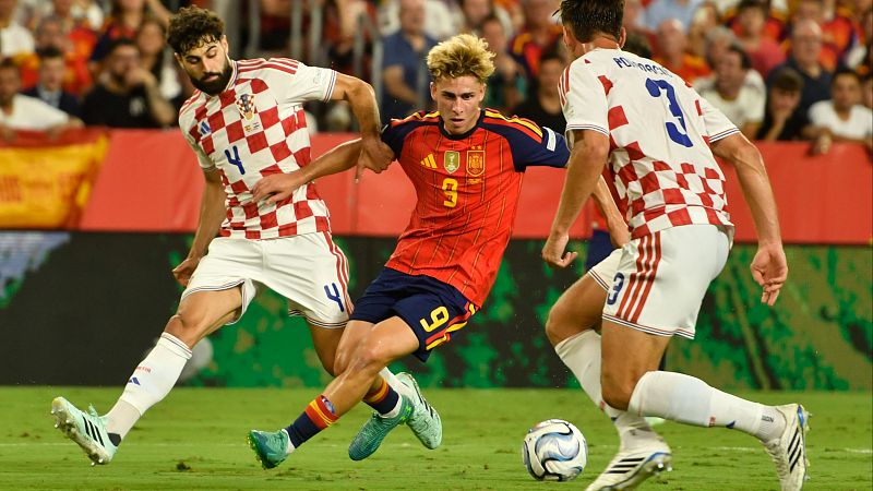 El jugador español Yeremy Pino avanza con el balón mientras es presionado de cerca por los defensores croatas Joško Gvardiol y Marin Pongračić en un partido de fútbol.