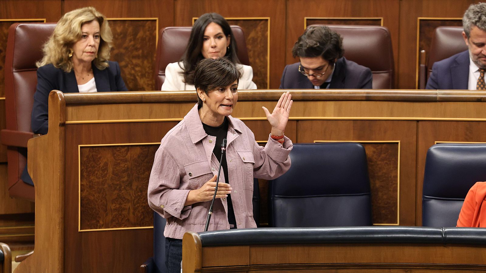 Isabel Rodríguez habla de pie en el Congreso de los Diputados, con Margarita Robles y Diana Morant sentadas detrás en la bancada azul del Gobierno.