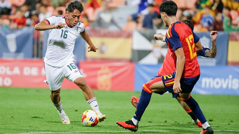 El futbolista mexicano Rodrigo L�pez controla el bal�n ante la marca del espa�ol Gabri Veiga durante un partido en un estadio con p�blico y publicidad de Movistar al fondo.