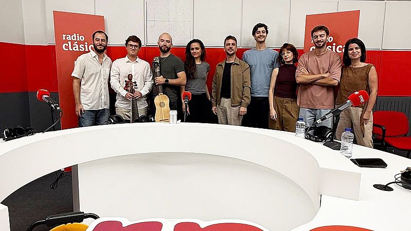 Nueve personas, entre ellos integrantes de Cantoría y presentadores de Radio Clásica, posan en el Estudio 206 de RNE tras una mesa con micrófonos y sosteniendo instrumentos antiguos.