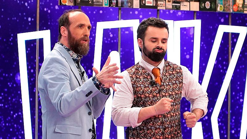 Eduardo Sáenz de Cabezón y Ricardo Moure gesticulan divertidos en el plató de "Órbita Laika", decorado con letras iluminadas y elementos retro de los noventa sobre un fondo violeta.