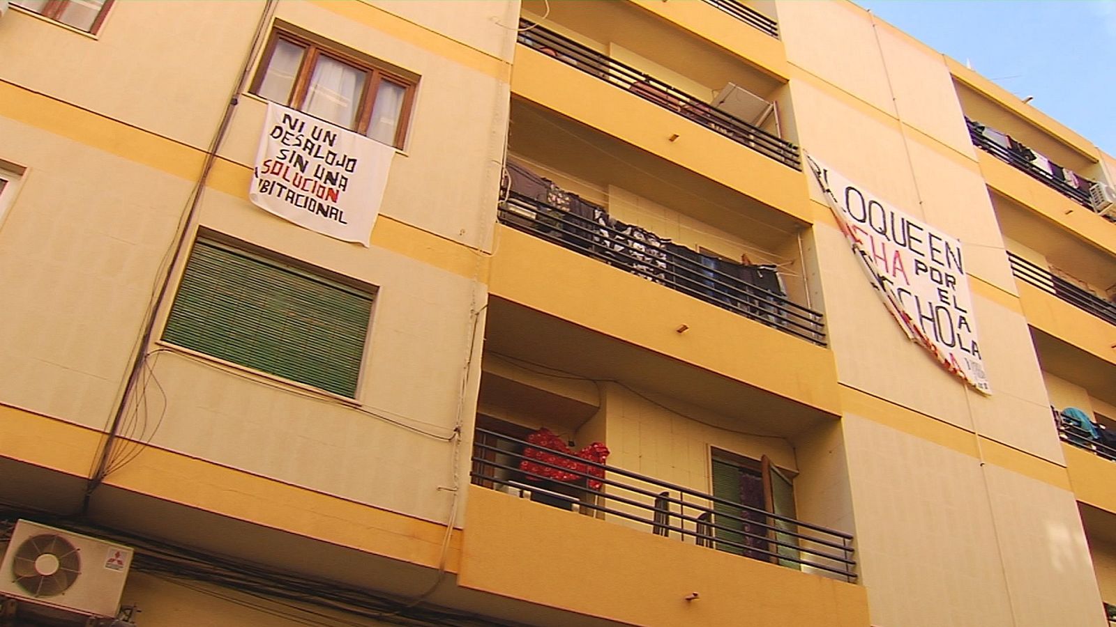 Fachada de un edificio en Alicante con pancartas de protesta donde se lee 'NI UN DESALOJO SIN UNA SOLUCIÓN HABITACIONAL' y 'BLOQUE EN LUCHA POR EL DERECHO A LA...'.