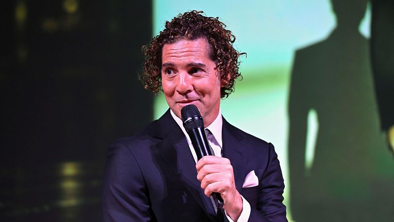 El cantante David Bisbal, de traje elegante y con su característico pelo rizado, sostiene un micrófono durante la presentación de su nuevo disco en Madrid.