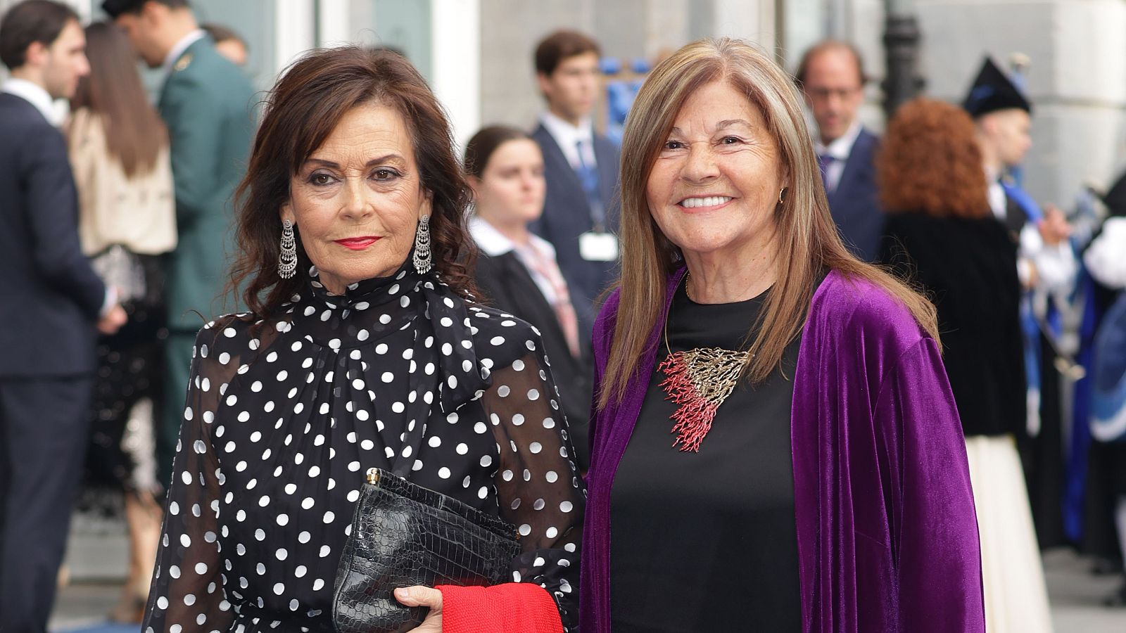 Paloma Segrelles, con blusa de lunares, y María Teresa Álvarez, con chaqueta de terciopelo morado, posan sonrientes en el exterior durante los Premios Princesa de Asturias.