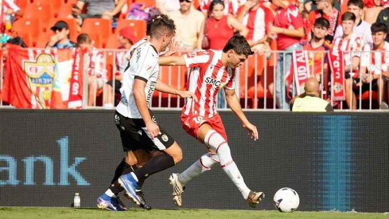 Nico Melamed con la camiseta rojiblanca de la UD Almer�a disputa el bal�n ante la intensa presi�n de un jugador rival en el estadio.