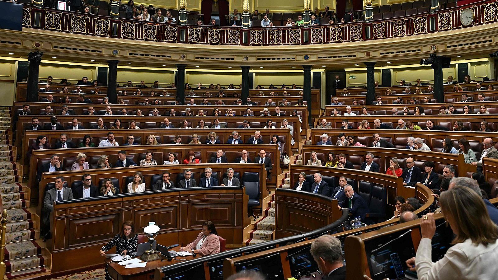 Vista general del hemiciclo del Congreso durante una sesión con diputados en los escaños y taquígrafas en primer plano.