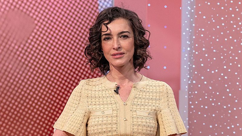 Plano medio corto de la actriz Blanca Romero mirando a cámara con expresión tranquila, cabello castaño ondulado y blusa de punto beige.