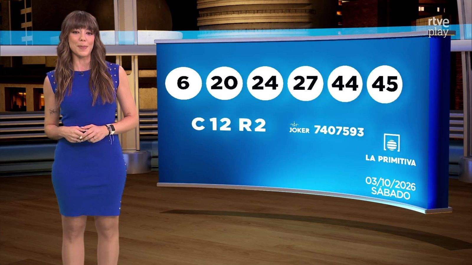Presentadora en plató junto a un panel digital azul que muestra los resultados de un sorteo con fecha de octubre de 2026.