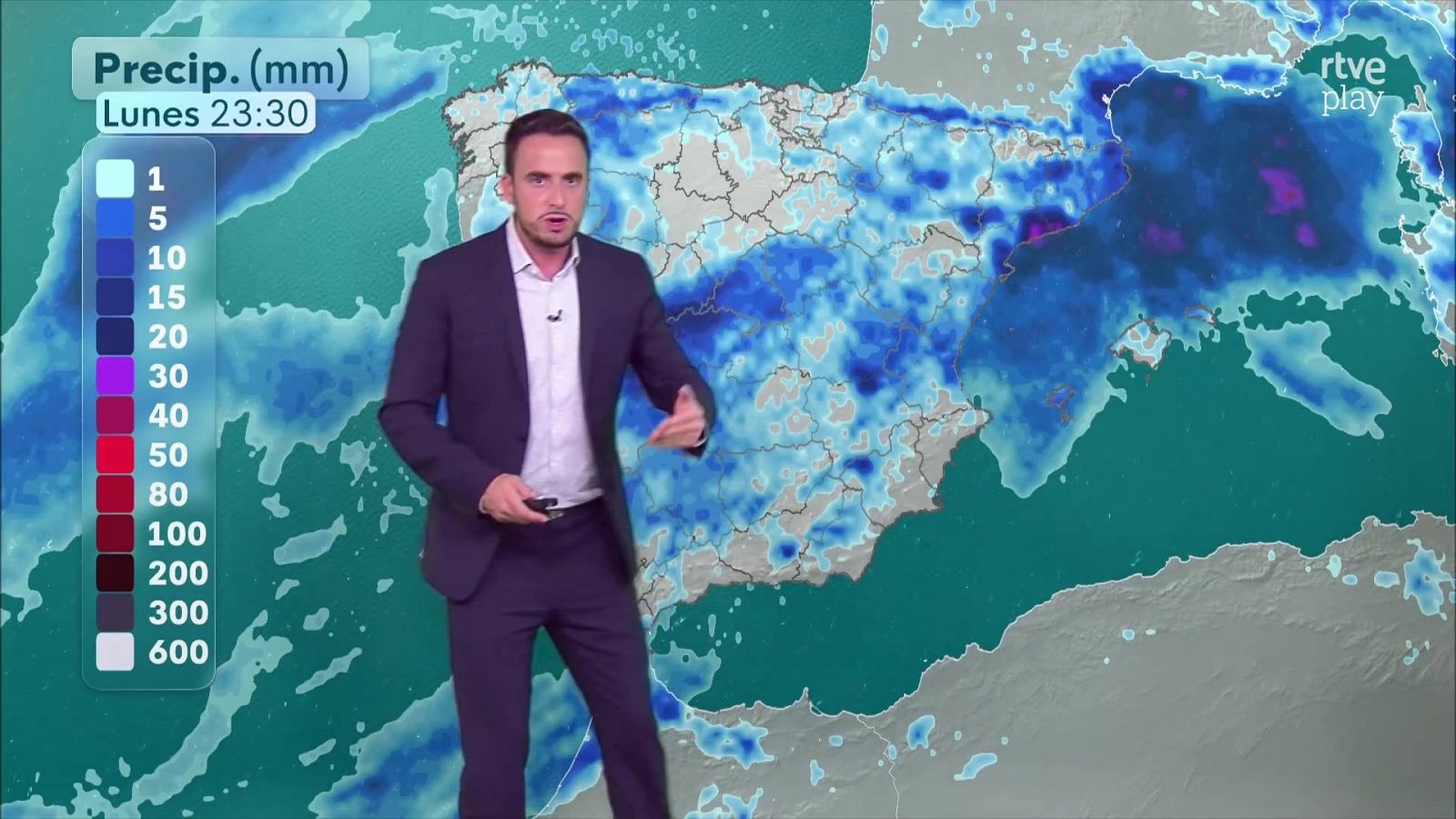 El presentador Marc Santandreu explica el mapa de precipitaciones en el plató de televisión con la península ibérica de fondo.