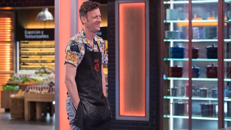 Edu Soto sonríe en el plató de MasterChef con camisa estampada y delantal negro manchado de harina.
