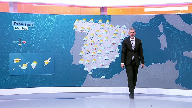 El presentador Albert Barniol camina por el plató frente a un gran mapa meteorológico de España que muestra tormentas y nubes.