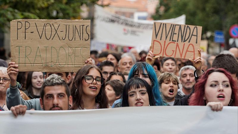 Jóvenes manifestantes protestan en una calle con pancartas y carteles hechos a mano exigiendo vivienda digna.