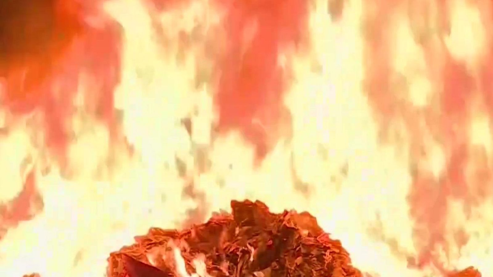 Plano corto de un intenso fuego con grandes llamaradas y ascuas incandescentes consumiendo residuos combustibles.