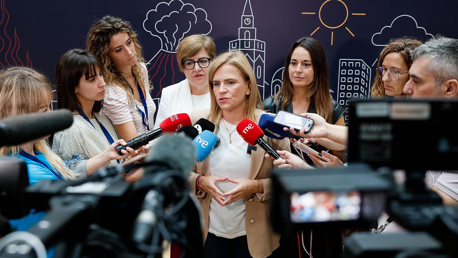 La presidenta del Cabildo de Tenerife atiende a los medios de comunicación rodeada de cámaras y micrófonos.