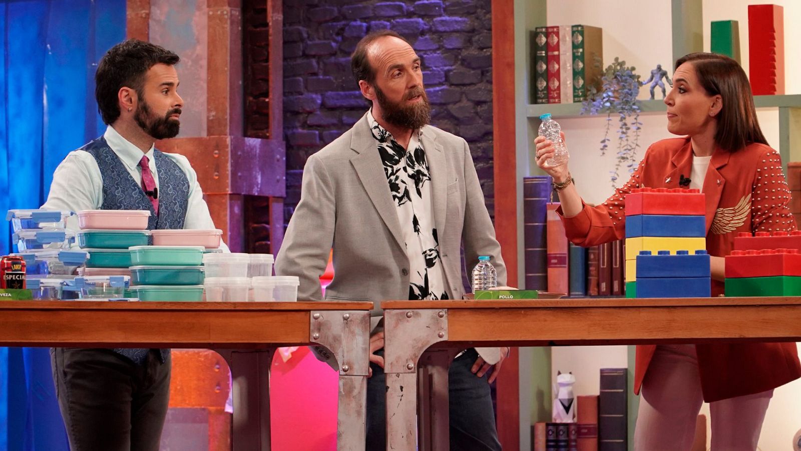 Tres divulgadores científicos participan en un plató televisivo junto a una mesa con recipientes y bloques de plástico.