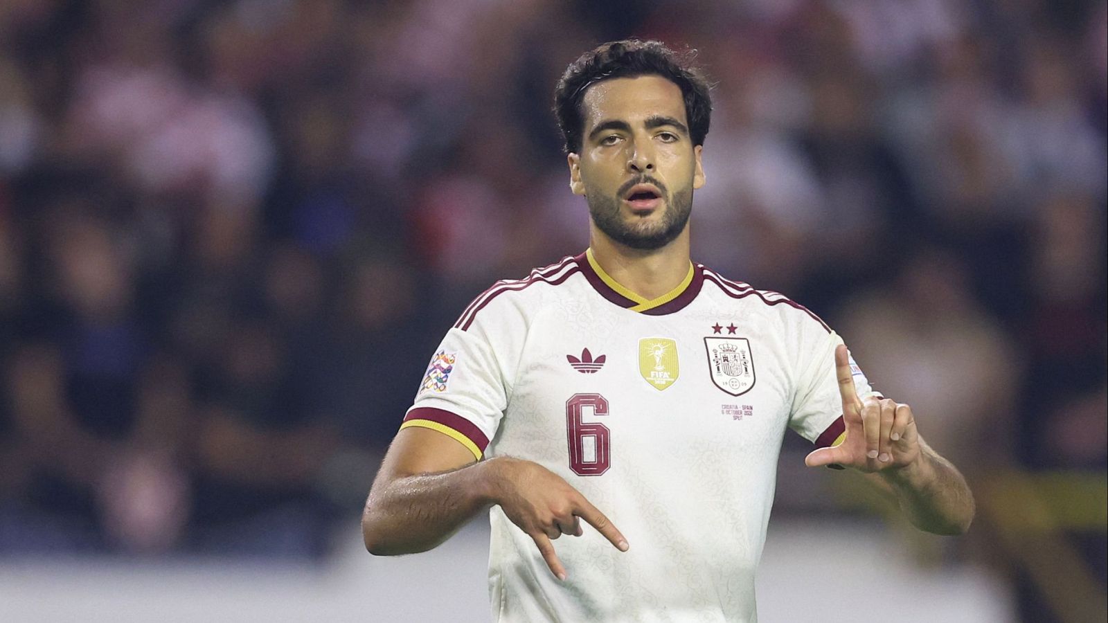 Plano medio del futbolista Mikel Merino con la equipación blanca de España, dorsal 6, gesticulando con expresión concentrada.