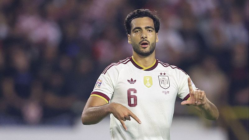 Plano medio del futbolista Mikel Merino con la equipación blanca de España, dorsal 6, gesticulando con expresión concentrada.