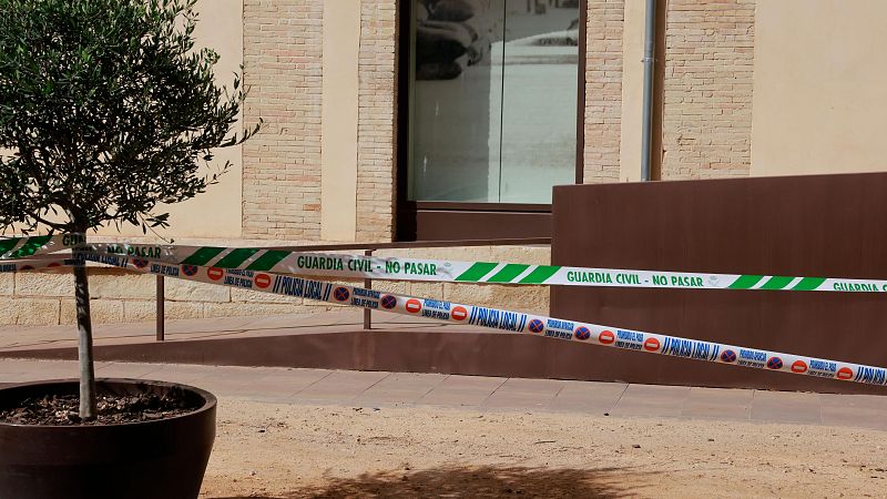 Acceso a un edificio acordonado con cintas de balizamiento policial de la Guardia Civil y Policía Local durante el día.